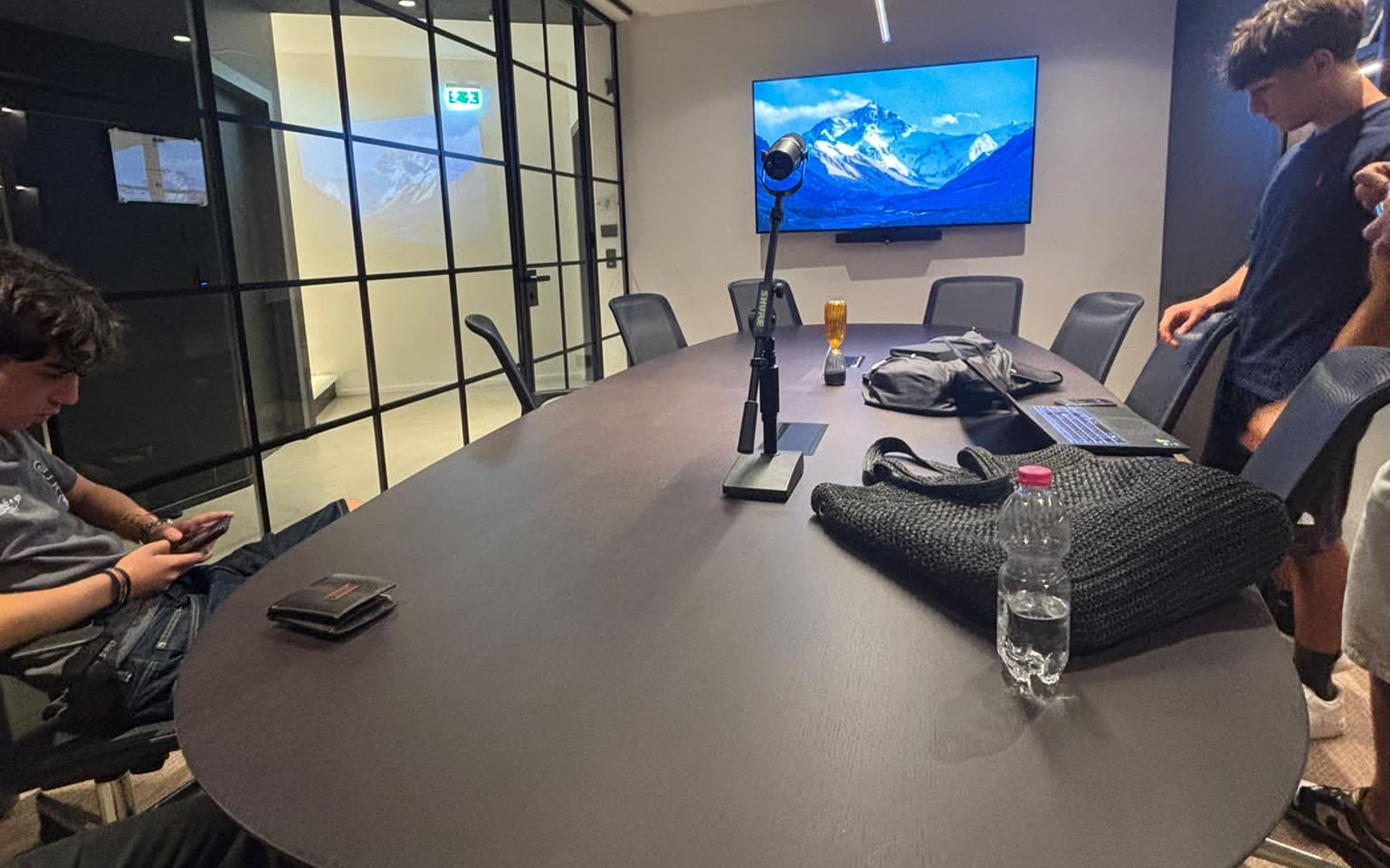 Una sala riunioni con il tavolo ovale, un microfono su asta, lo schermo acceso e alcuni di noi attorno, la sera in cui abbiamo visto la location del primo evento